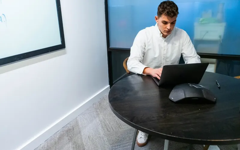 Homem com celular e notebook no escritório