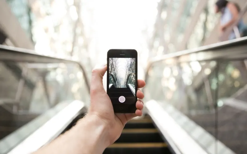 Mãos com celular e câmera na cidade