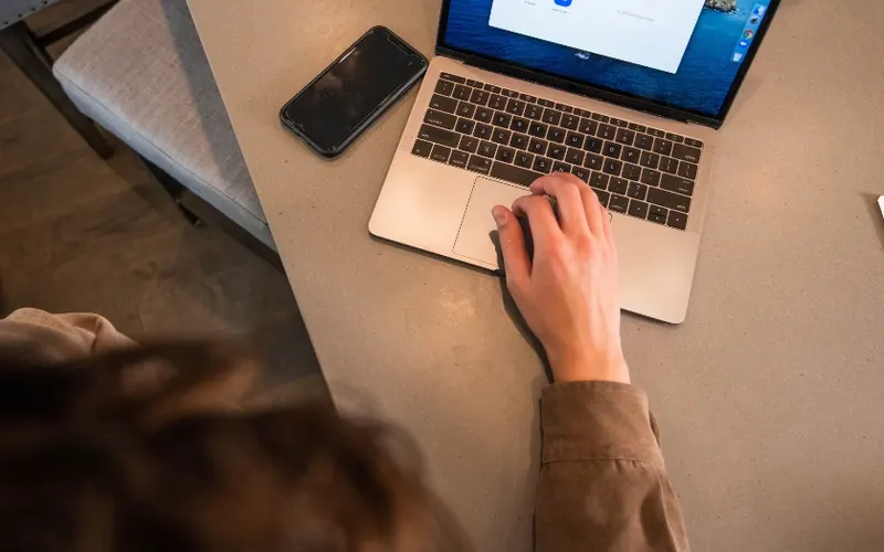 Mãos com celular e notebook no escritório