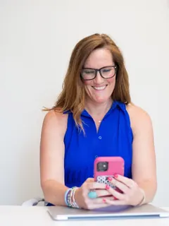Mulher com celular e notebook no escritório